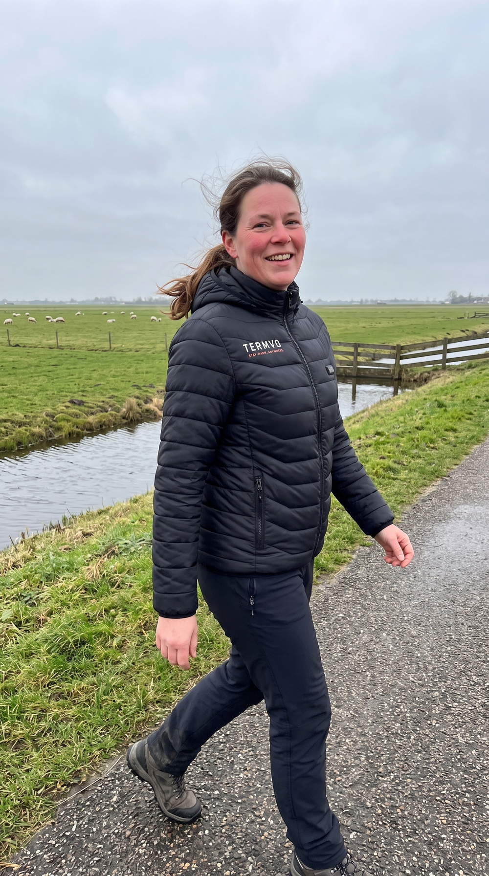Vrouw wandelt langs het water in een verwarmde TERMVO jas