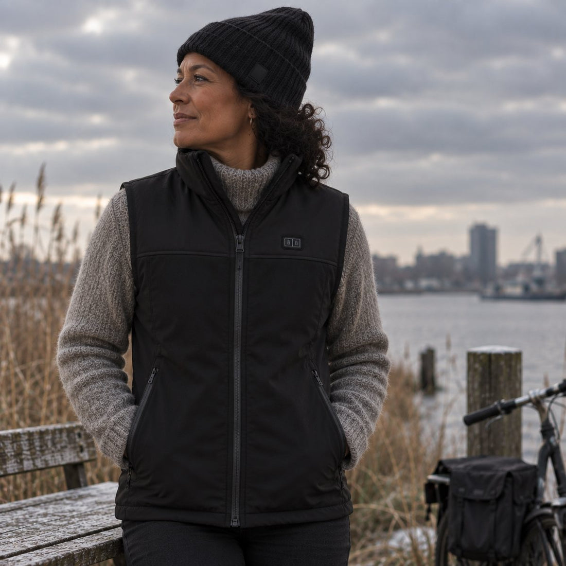 Vrouw in een zwarte verwarmde bodywarmer aan het water