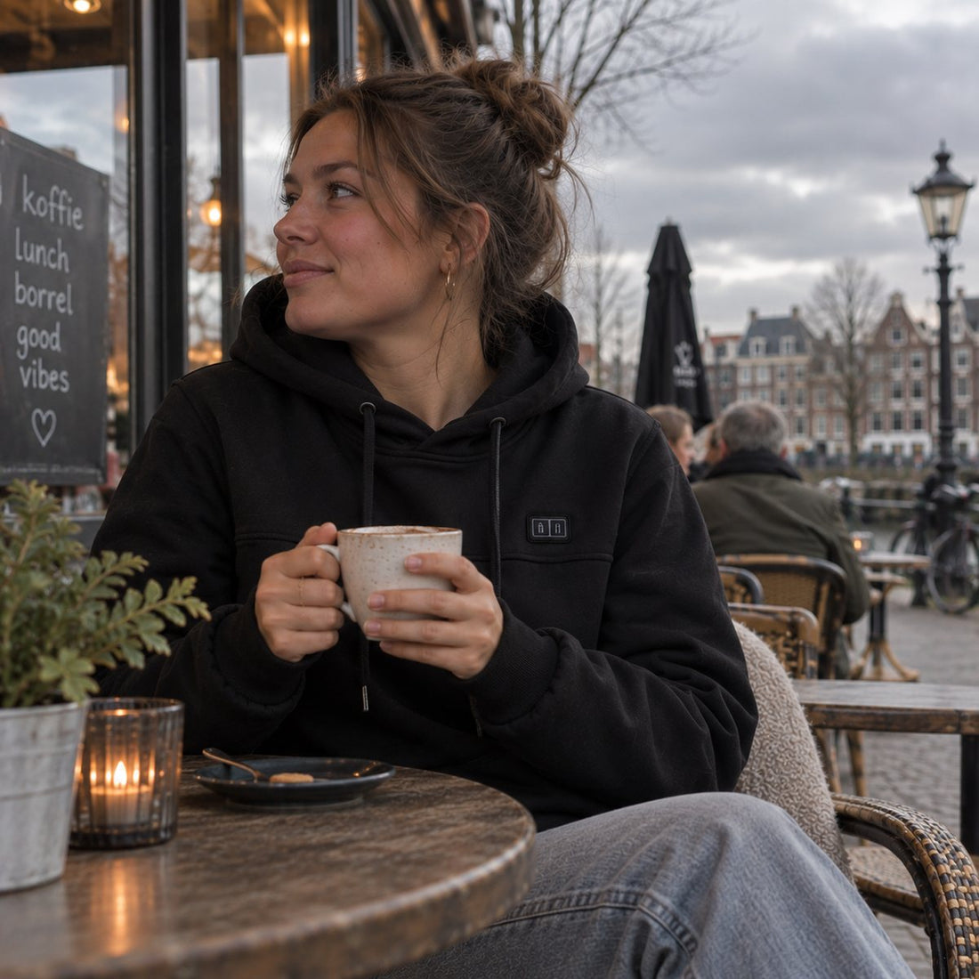 Vrouw in een zwarte verwarmde hoodie op een terras