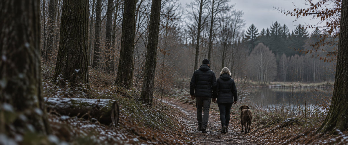 Stel in zwarte verwarmde jassen wandelt met hun hond door een winters bos